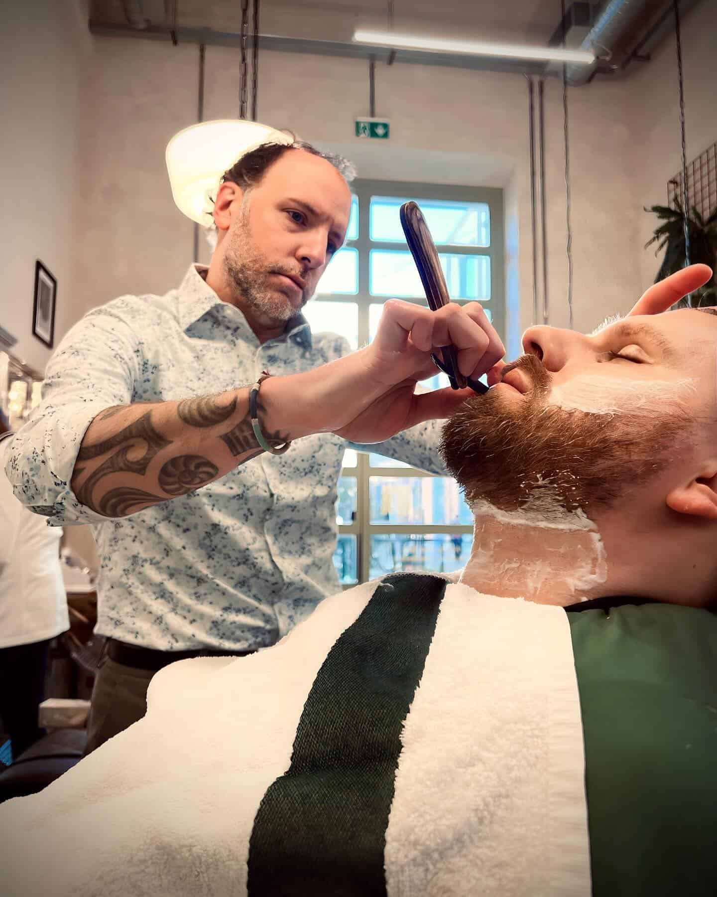 barber shaving a client witha straight razor