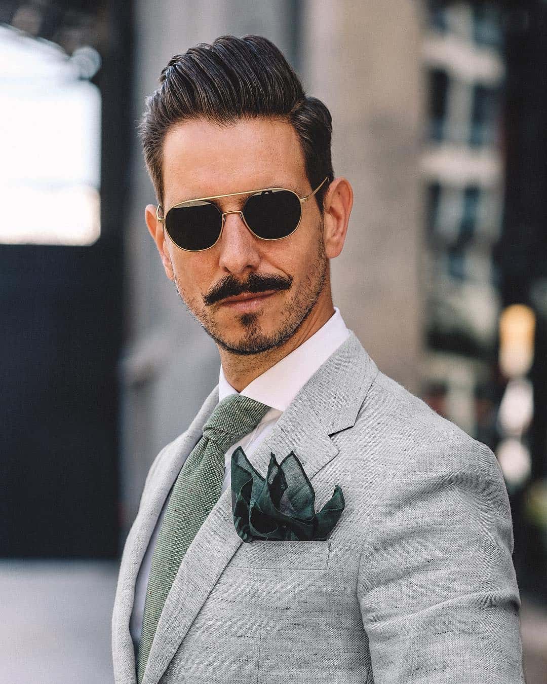 man in a suit wearing aviator style sunglasses