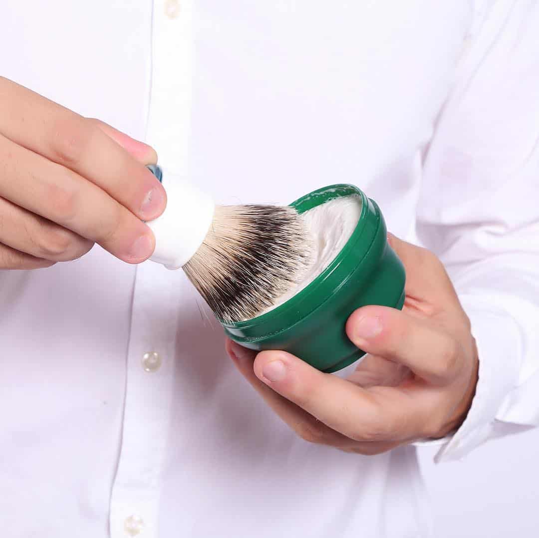man dipping brush in to a shaving cream