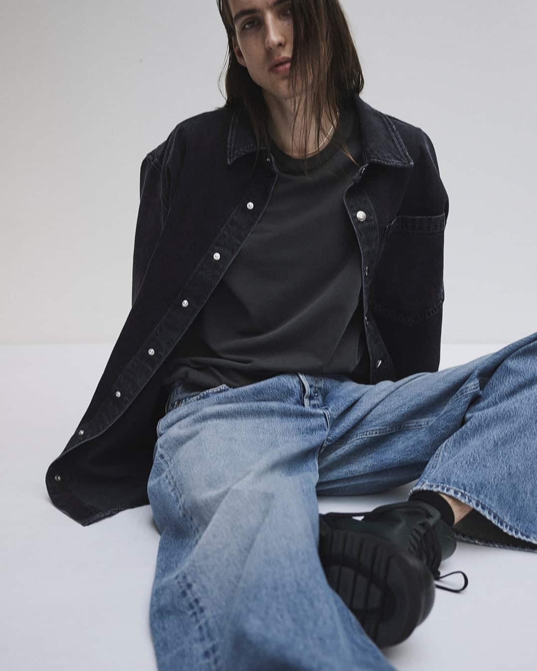 man wearing a black denim shirt and light-washed jeans