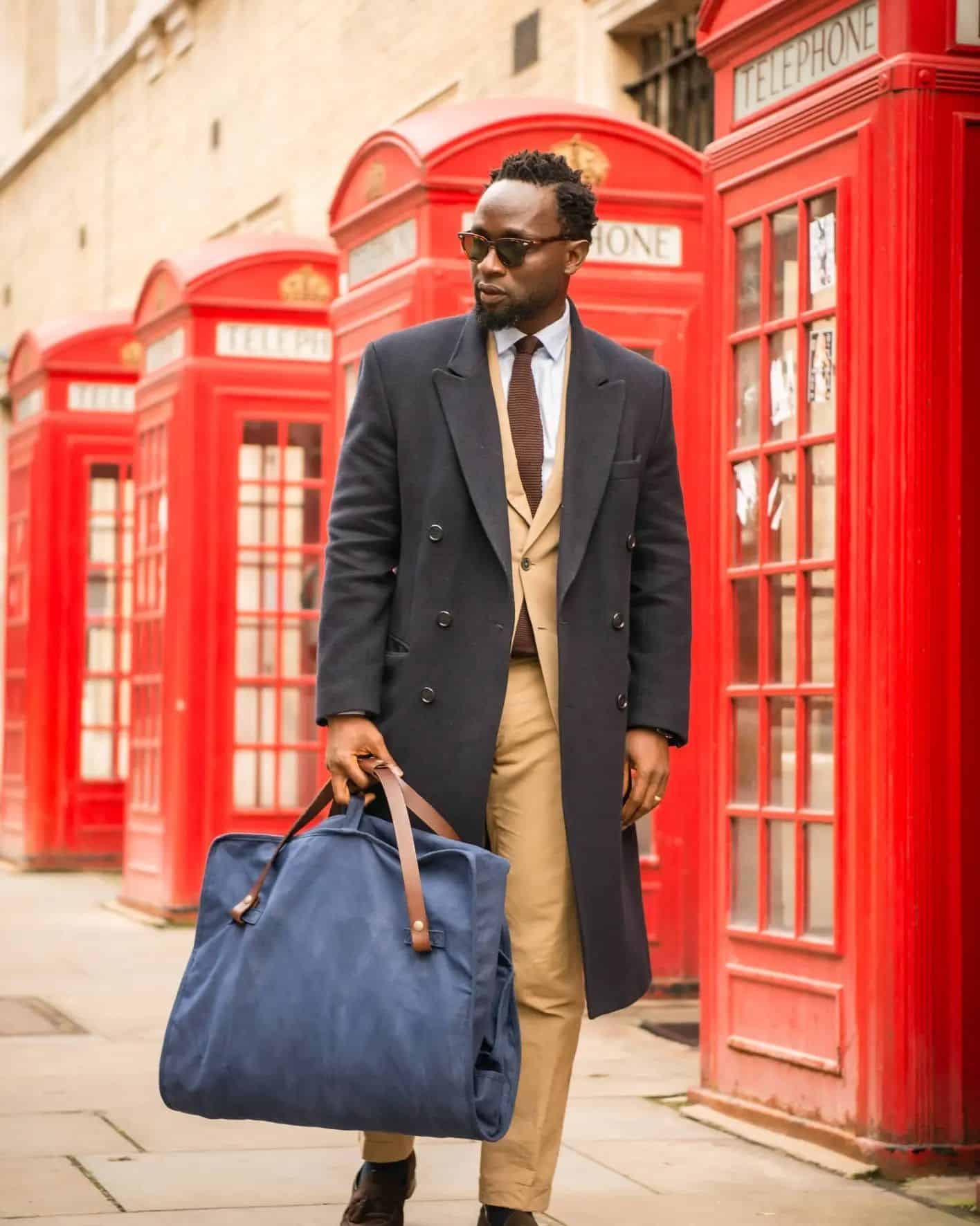 Dark Academia fashion: man wearing a long black coat carrying a suit bag