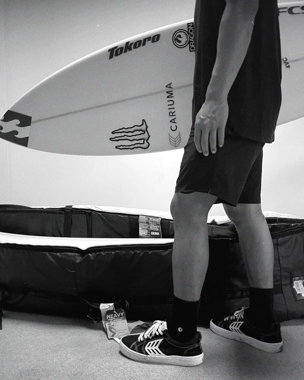 man in black socks and shoes carrying a surfboard