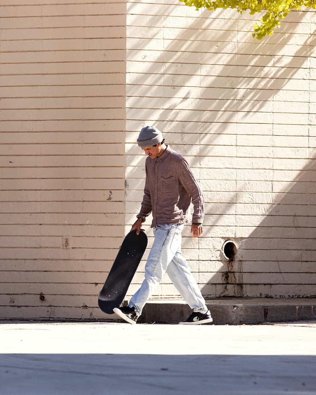 man walking on the street while carrying a skateboard