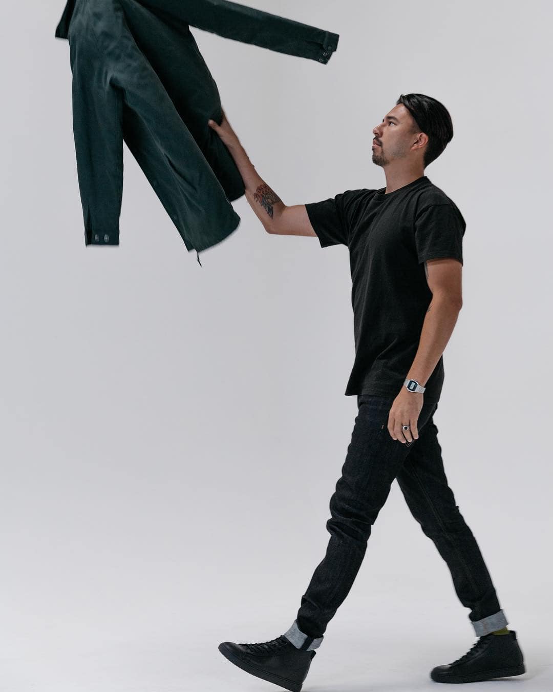 Rockstar aesthetic: man in black outfit catching a jacket mid-air