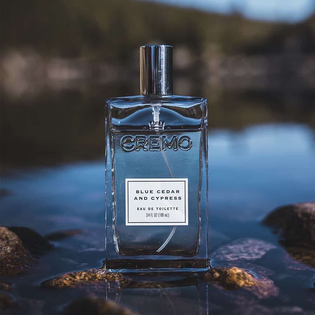 a bottle of blue cedar and cypress cologne on a body of water