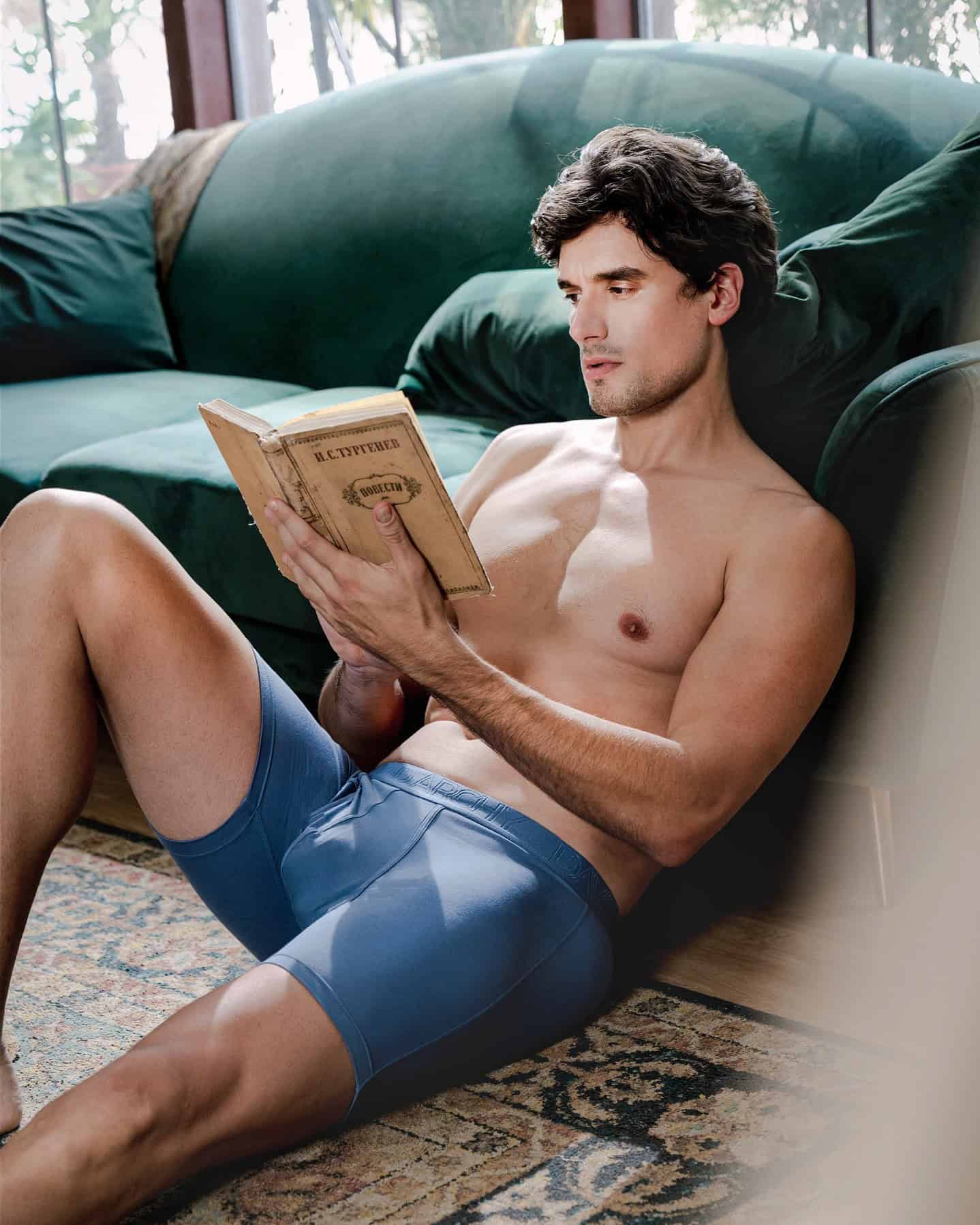 man in a boxer briefs reading a book