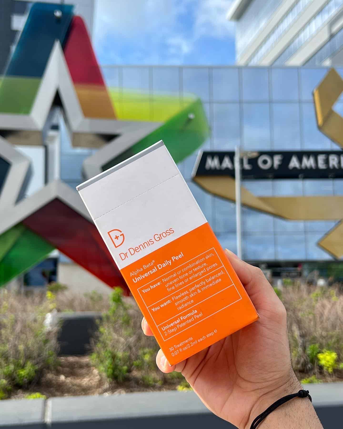 holding a box of universal daily peel by dr dennis gross