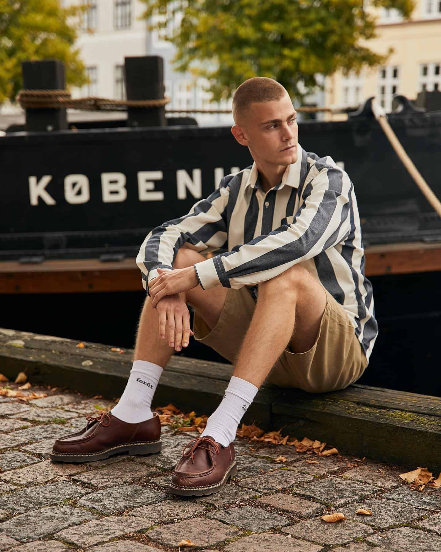 man sitting by the docks wearing shorts and shirt