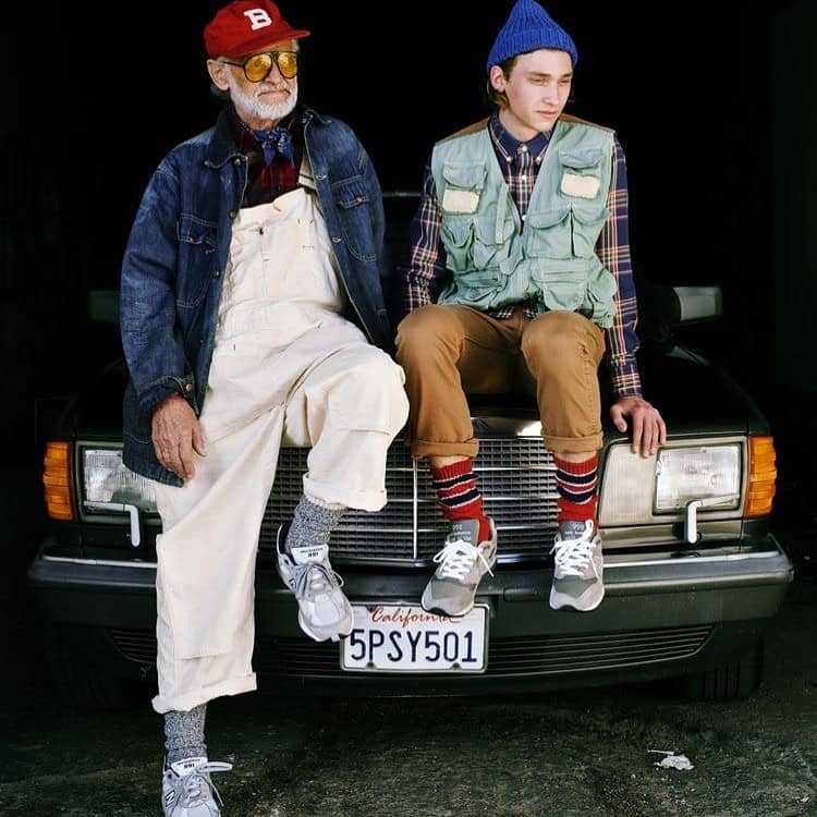 a young and old man sitting on the hood of a car