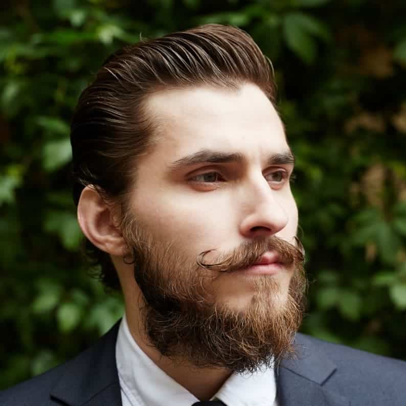 man with a slick hair and curled mustache and full beard