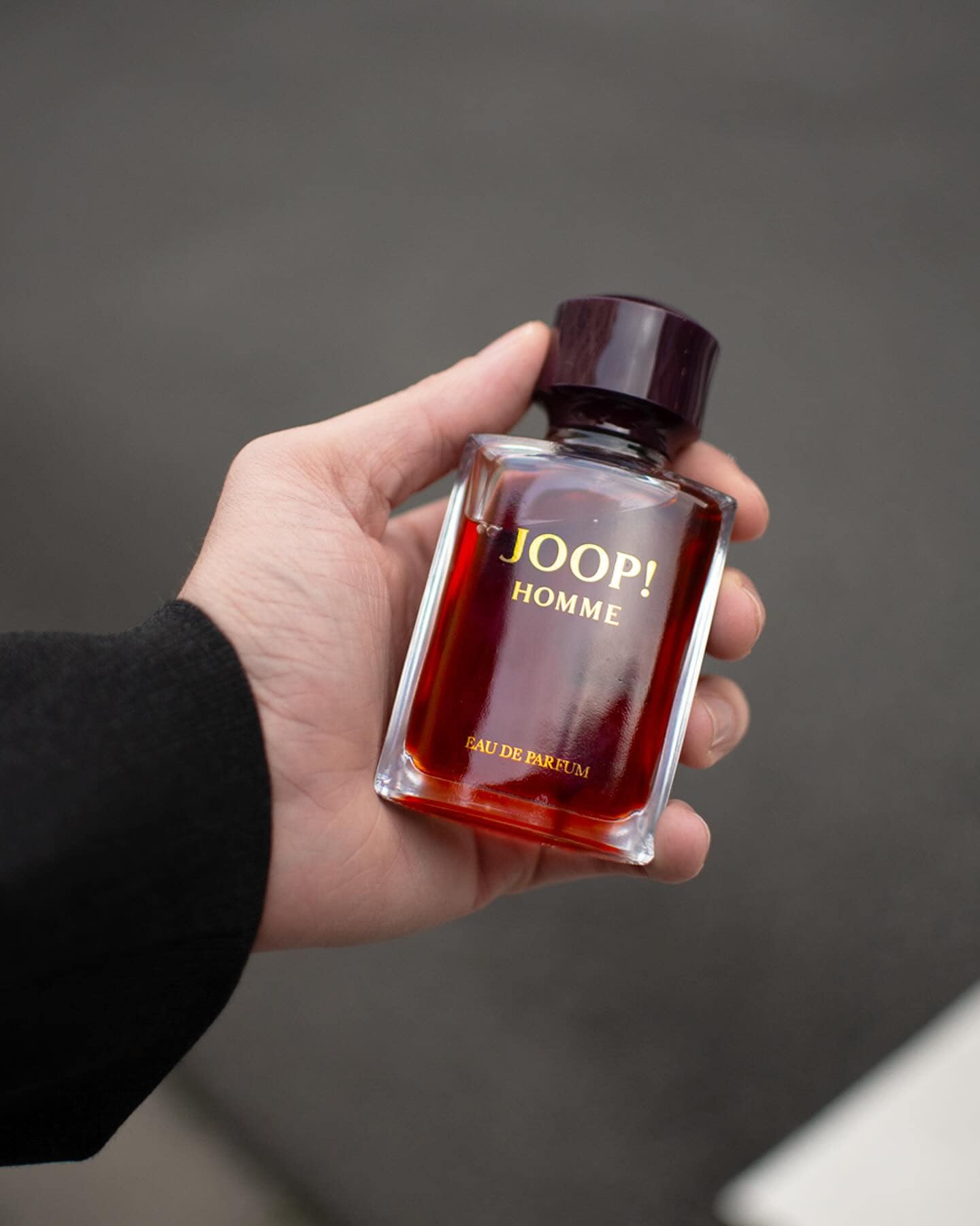 holding a bottle of joop homme eau de parfum