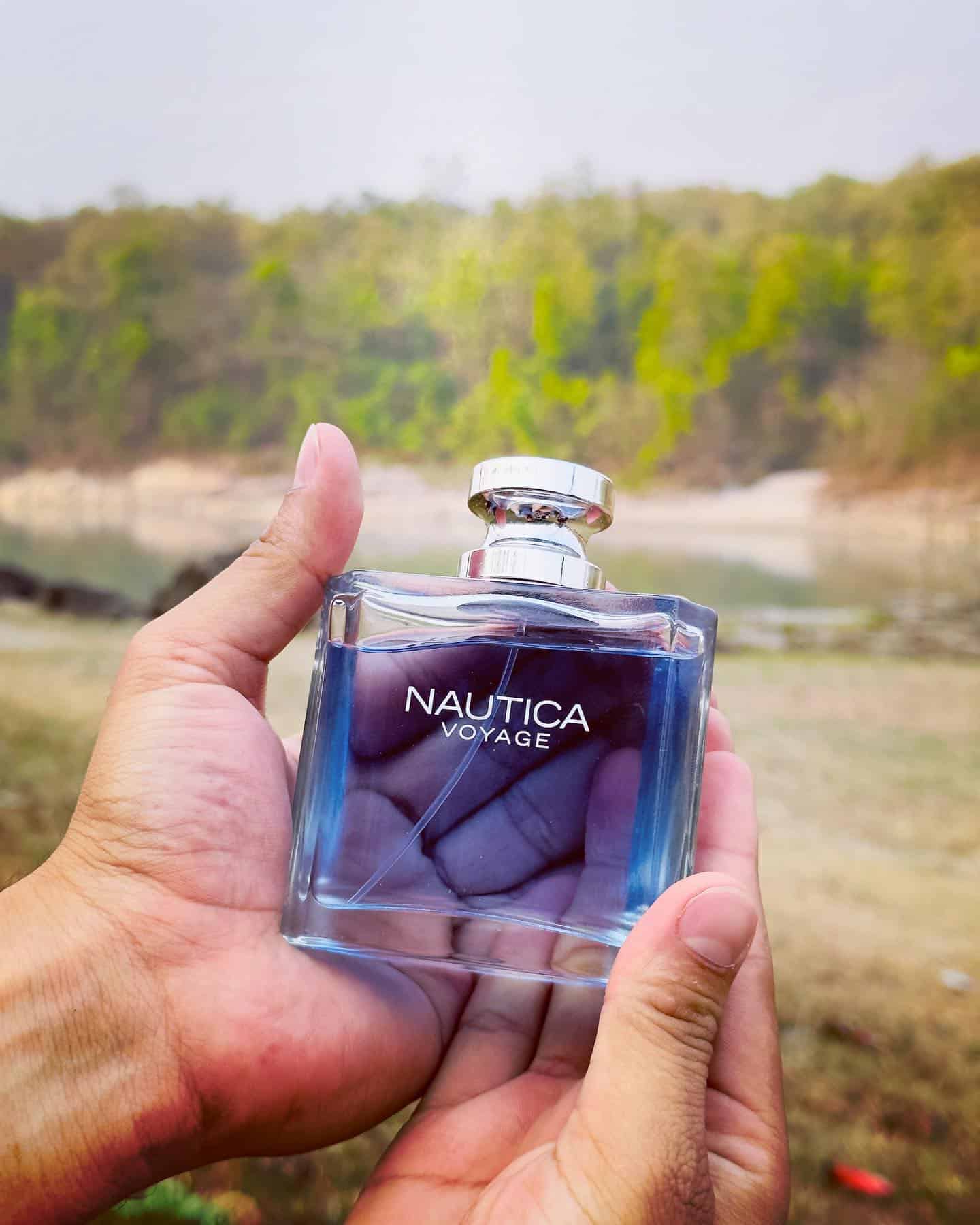 holding a bottle of nautica voyage cologne with both hands