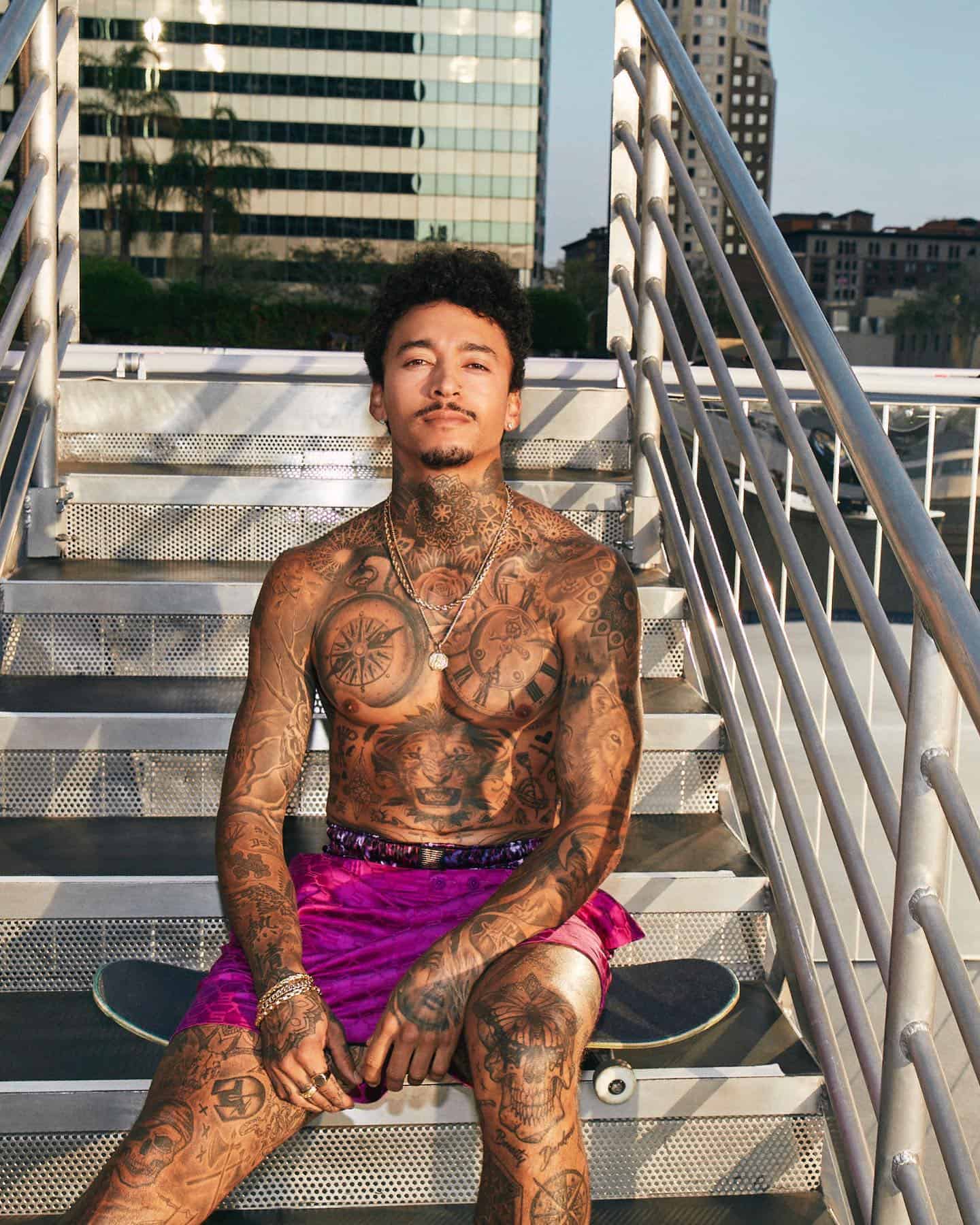 shirtless Nyjah Huston sitting on a skateboard