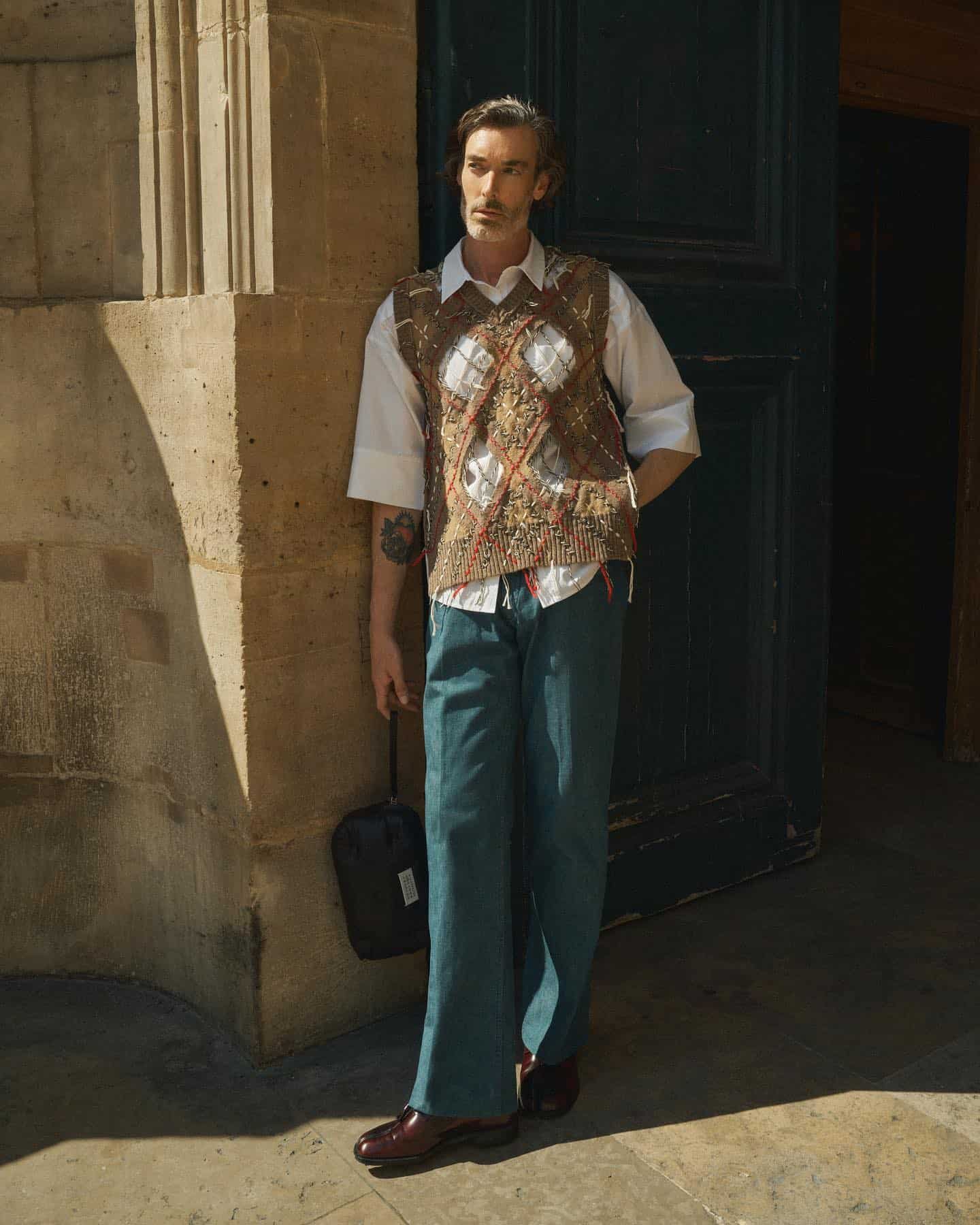 man wearing a vest over a shirt and a bell-bottom jeans