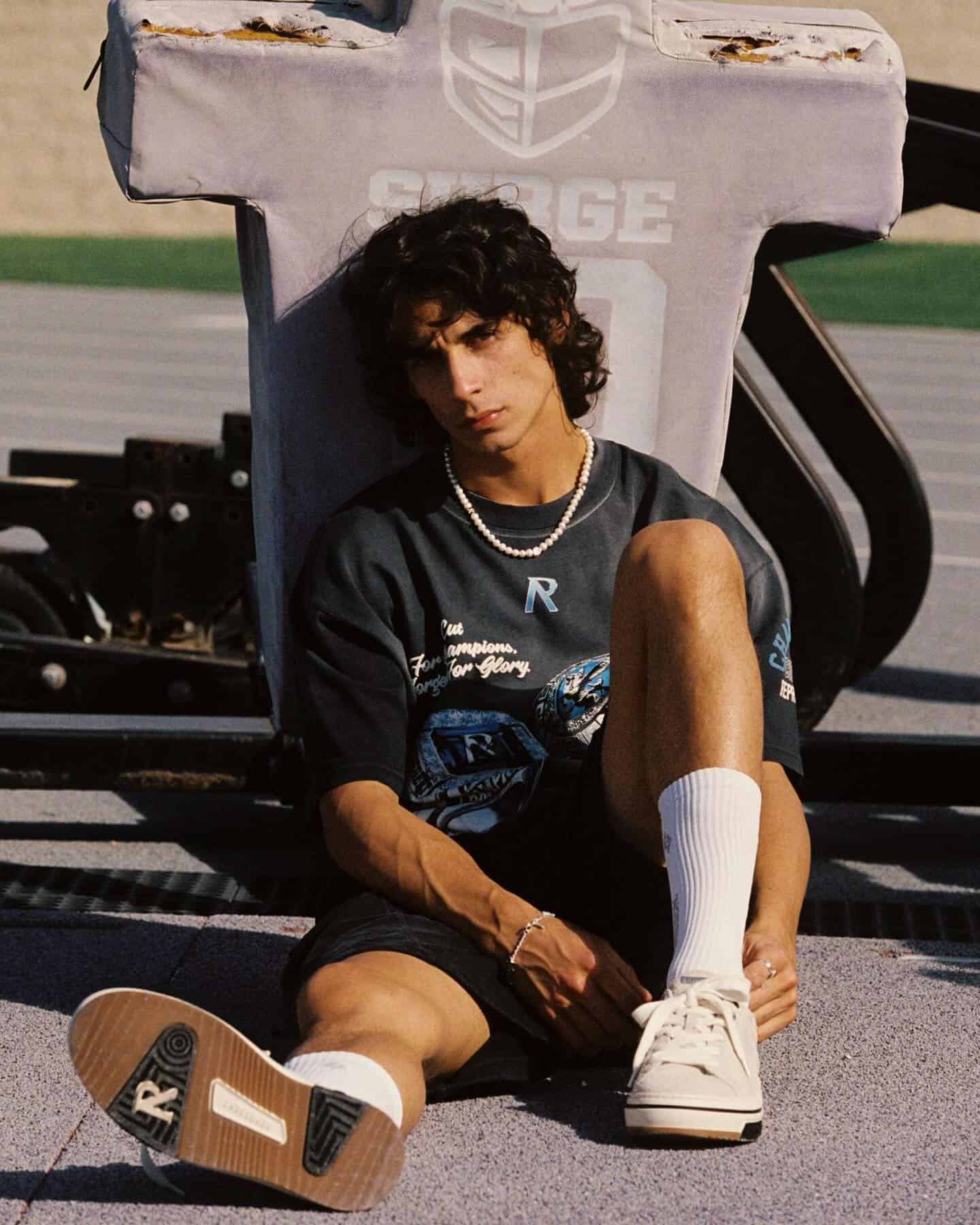 man in a black t-shirt and black shorts sitting on the ground