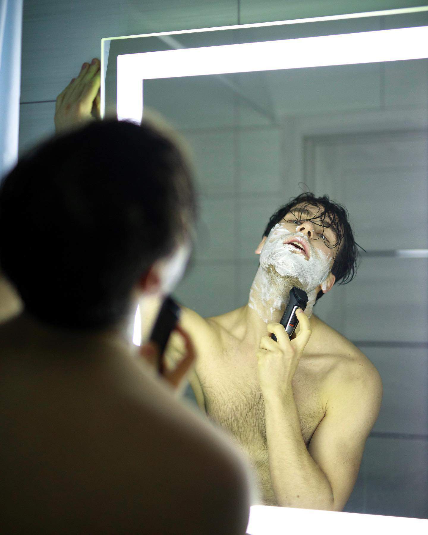 man using an electric shaver to shave beard