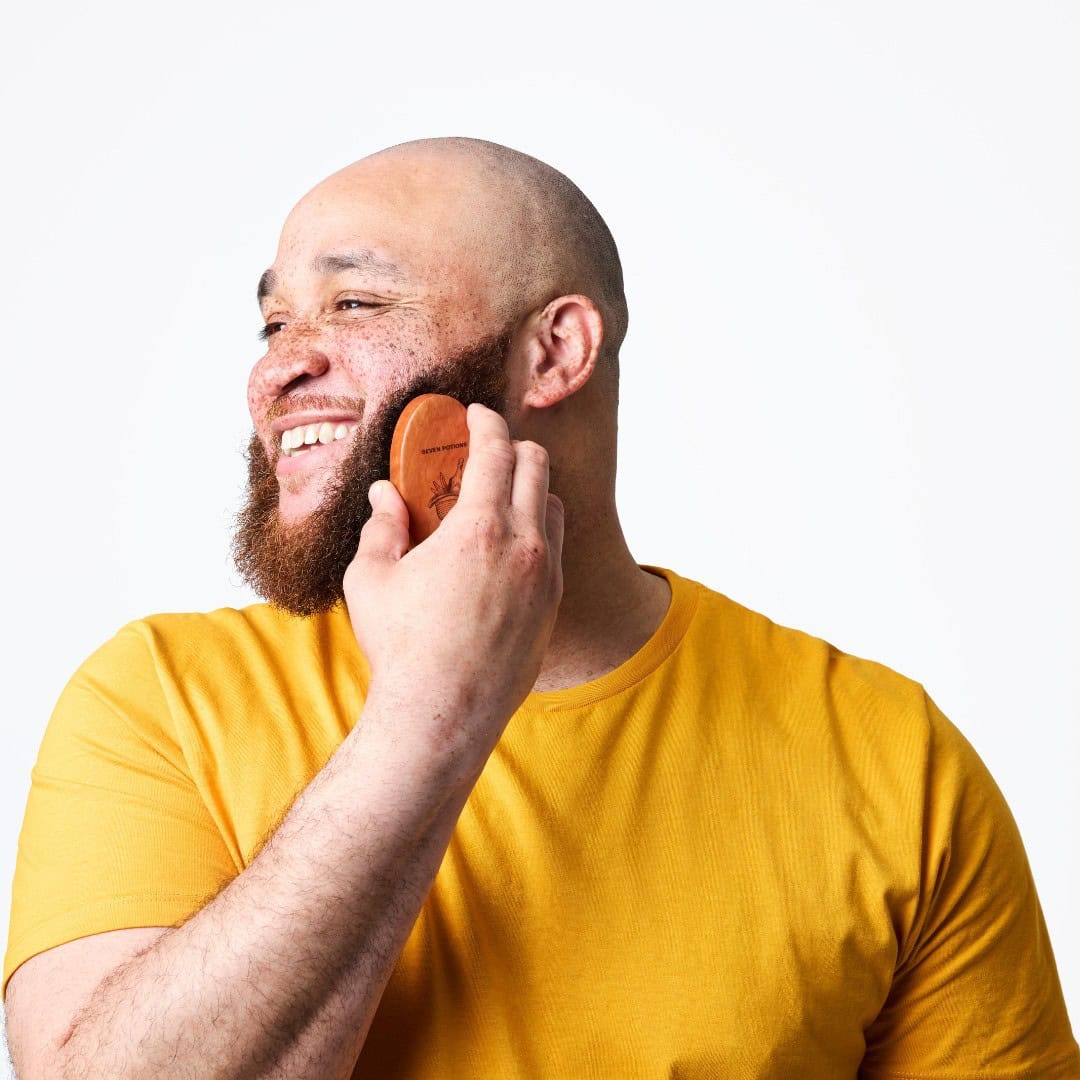 man smiling while using the seven potions beard brush
