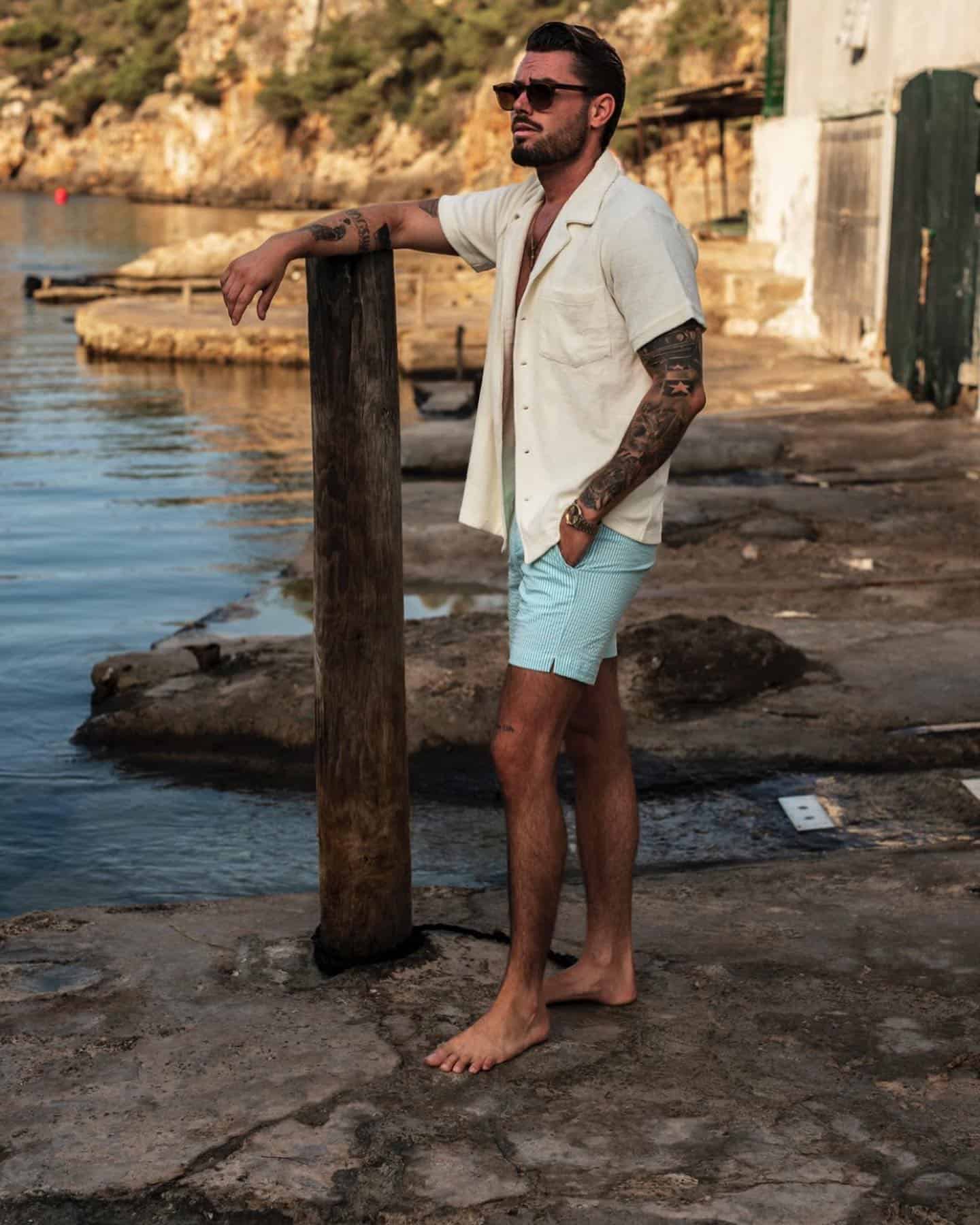 Surfer style: man in an unbuttoned shirt and swim pants