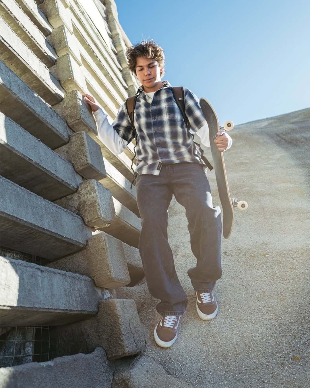 Skater style: a young man going down a slope while carrying a skateboard