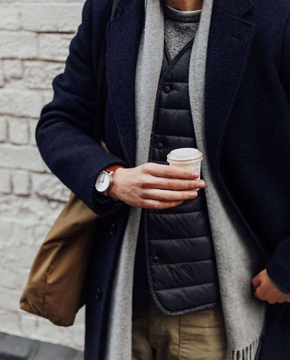 man wearing a wool coat while holding a cup of coffee