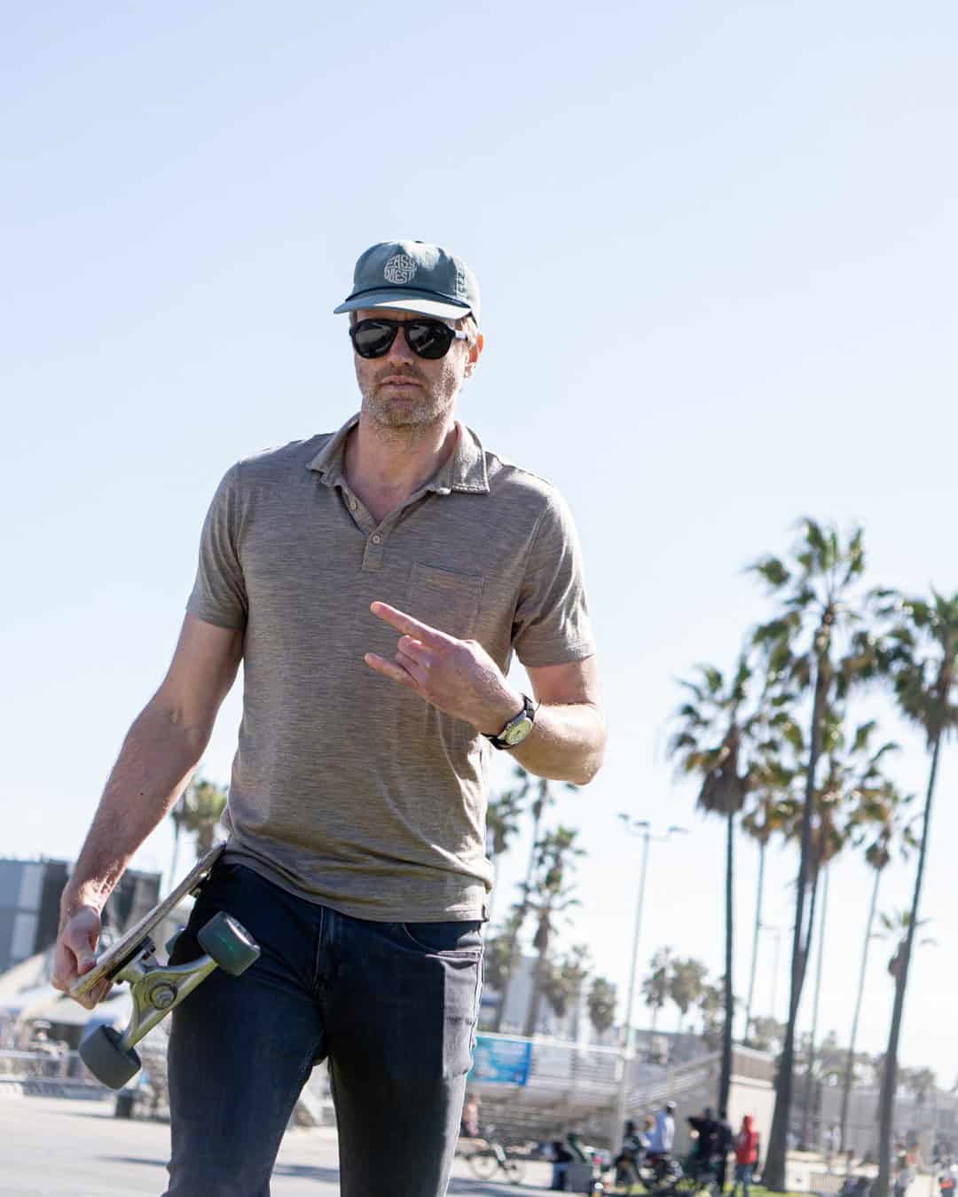 man carrying a skateboard wearing the Wolly short sleeve Polo shirt
