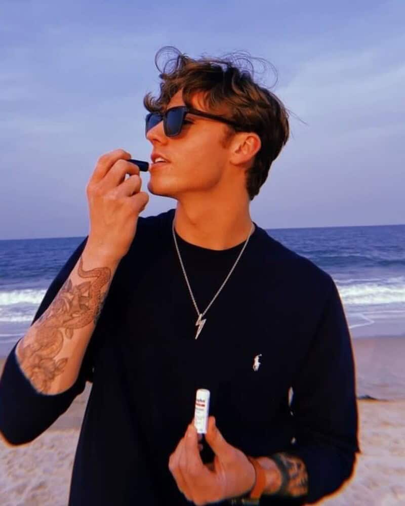 man at the beach applying the aquaphor lip repair lip balm