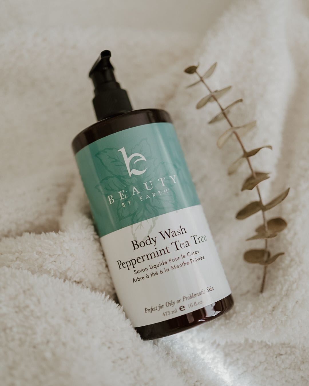 a bottle of peppermint tea tree body wash by beauty by earth on a towel