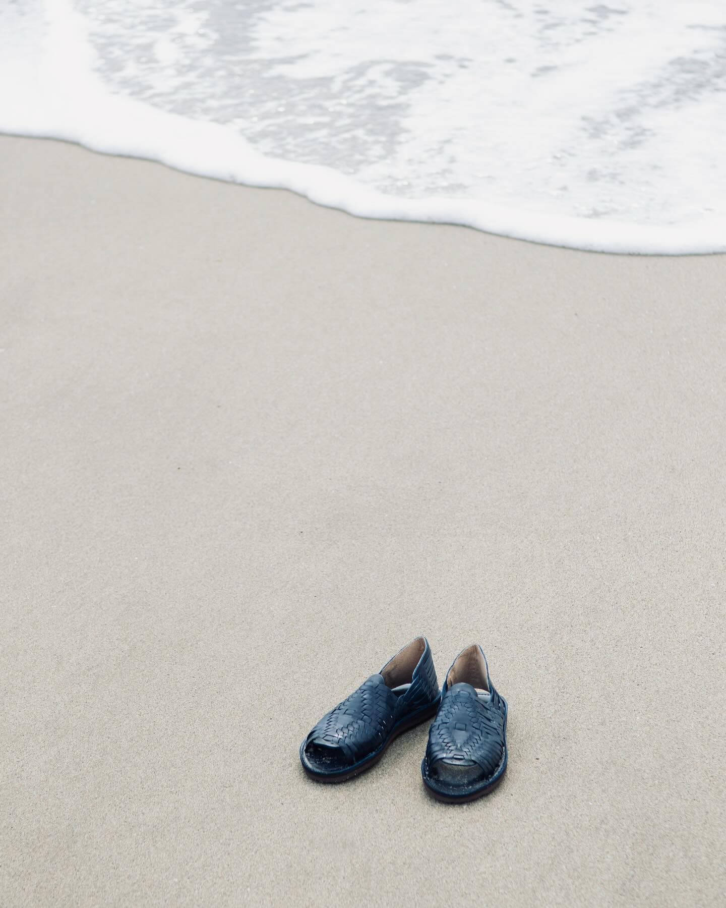 a pair of black huarache sandals at the beach