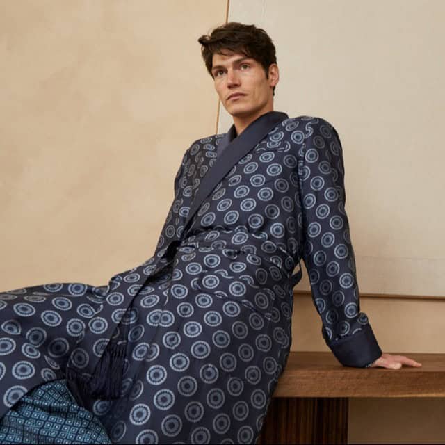 man leaning on a table wearing a silk robe by derek rose