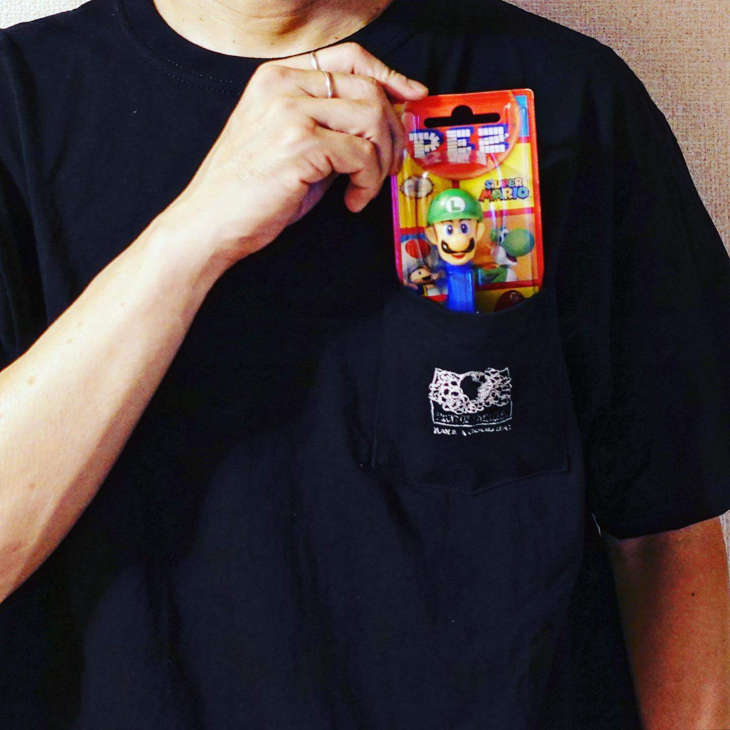 man putting a luigi pez despenser into t-shirt front pocket