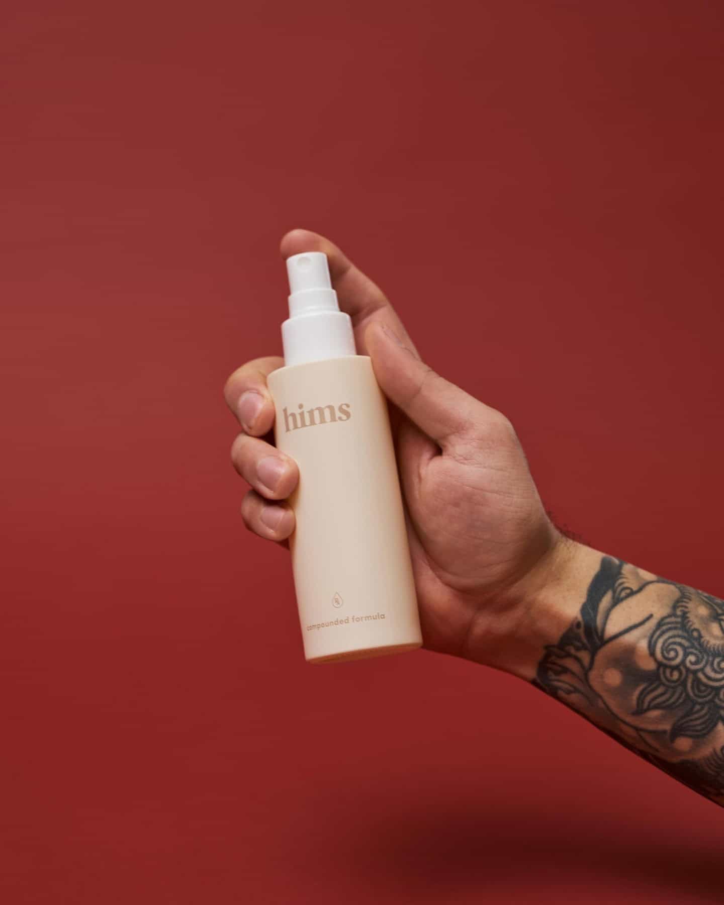 holding a bottle of hims rx hair loss spray