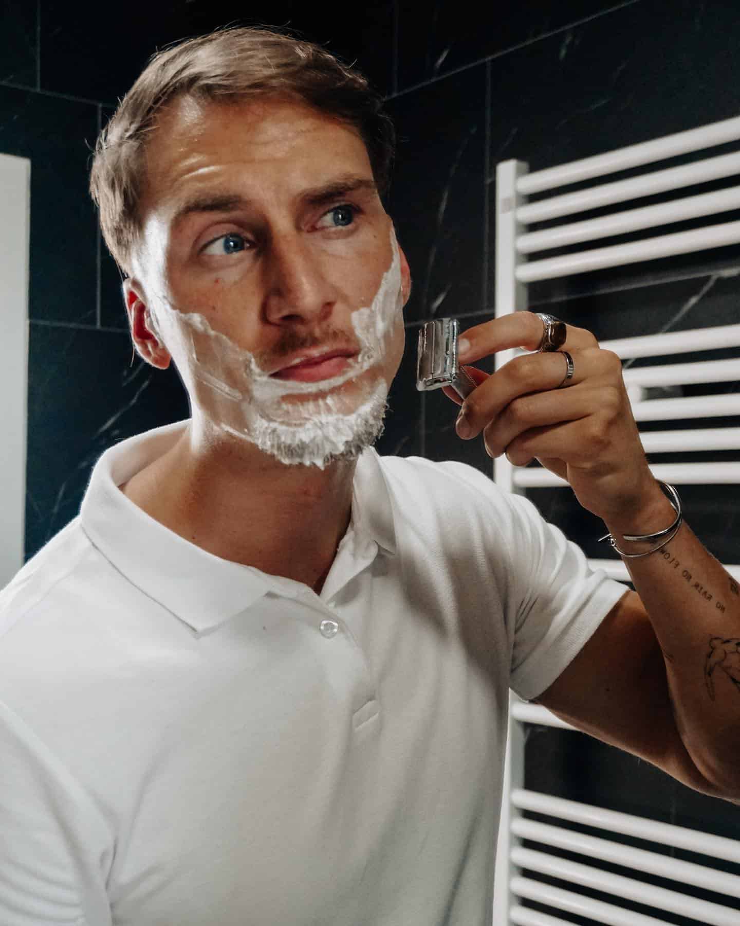 man using a safety razor to shave beard