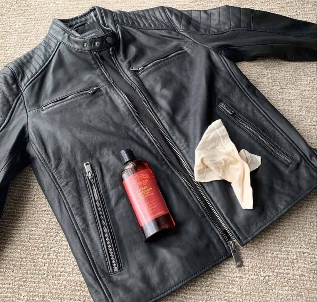 a bottle of leather honey leather conditioner on top of a leather jacket