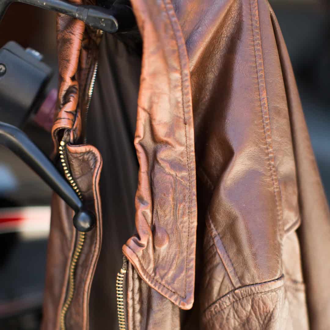 a leather jacket hanging on a motorcycle handlebar