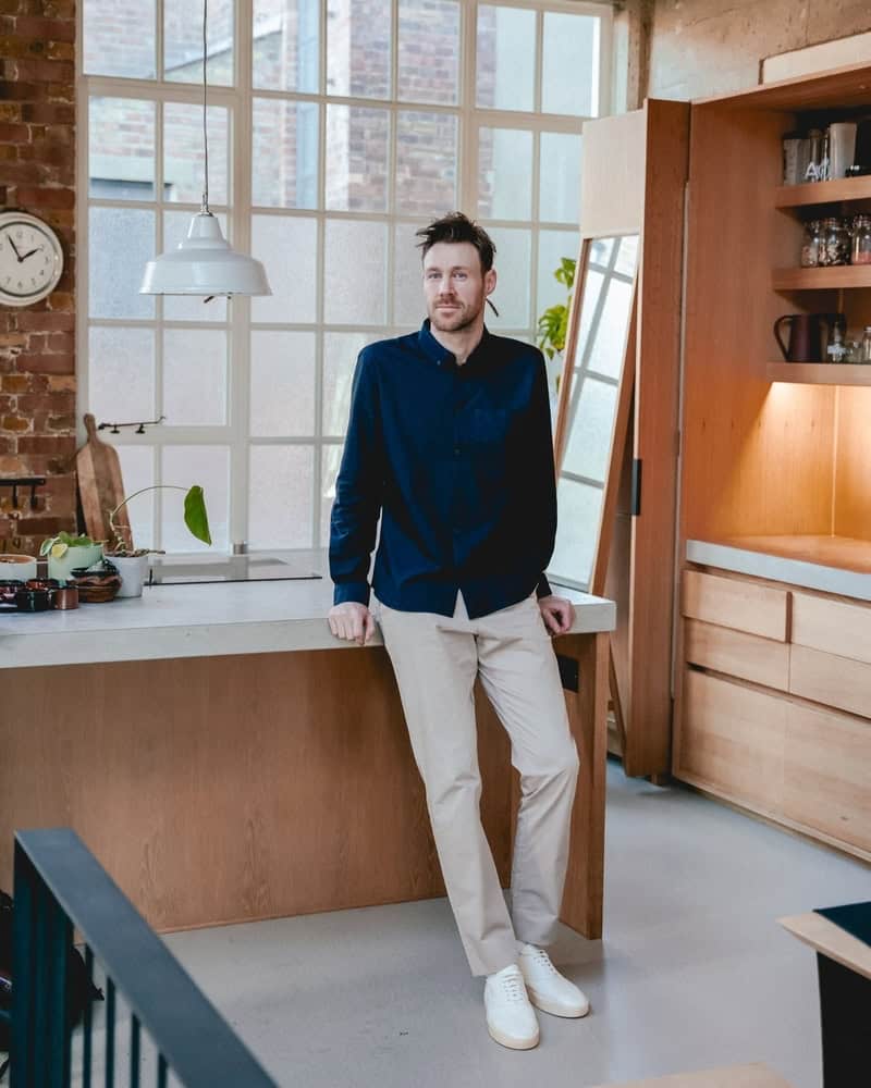 man in a blue shirt leaning on a desk