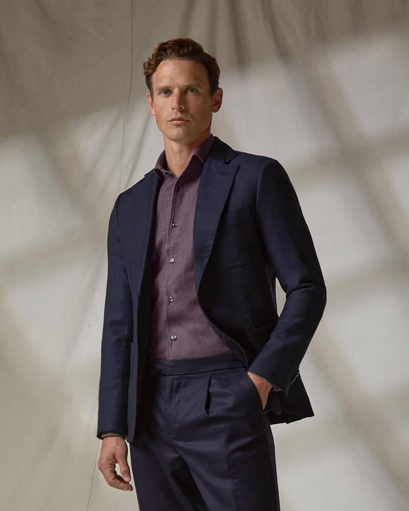 man wearing a navy suit: best dress shirt brands
