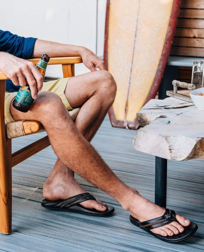 man sitting on a chair while holding a beer bottle