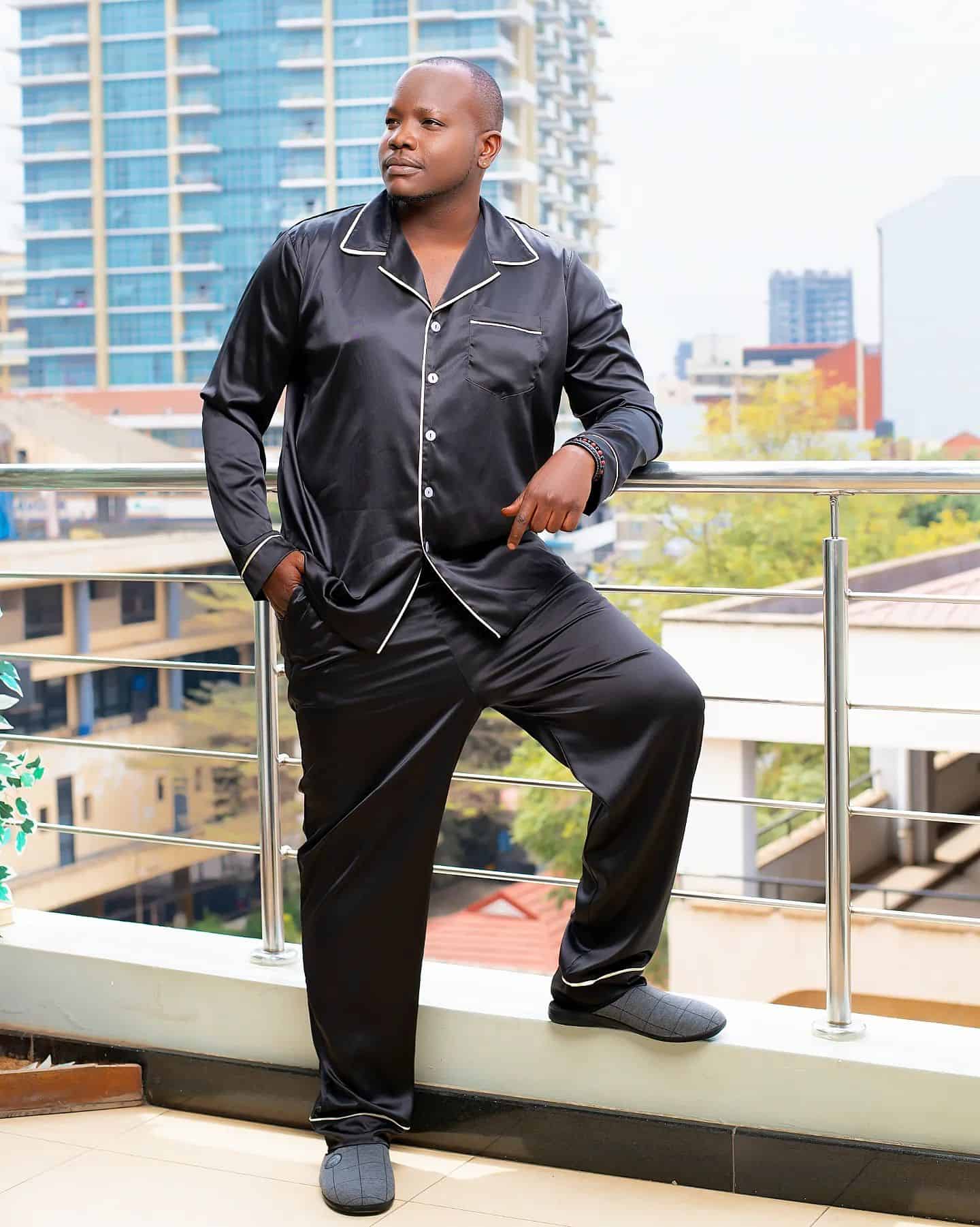 man standing outside a balcony wearing a pair of black silk pajamas