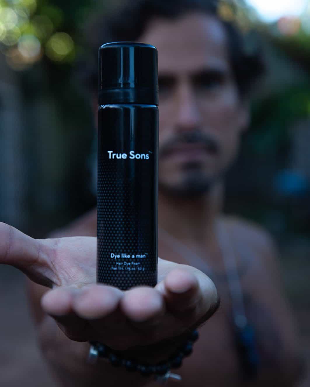 man holding up a bottle of true sons beard dye