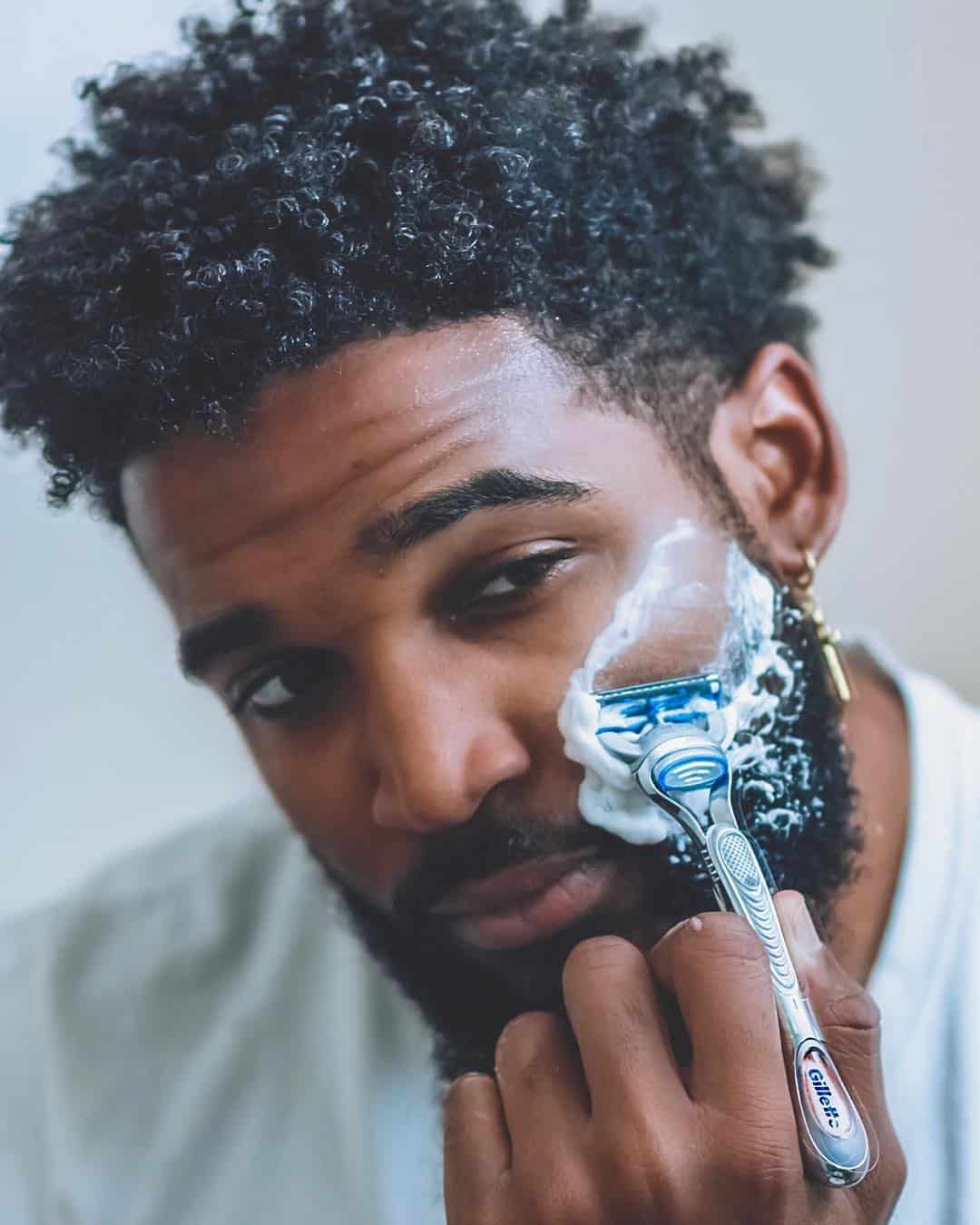man using a safety razor to shave beard