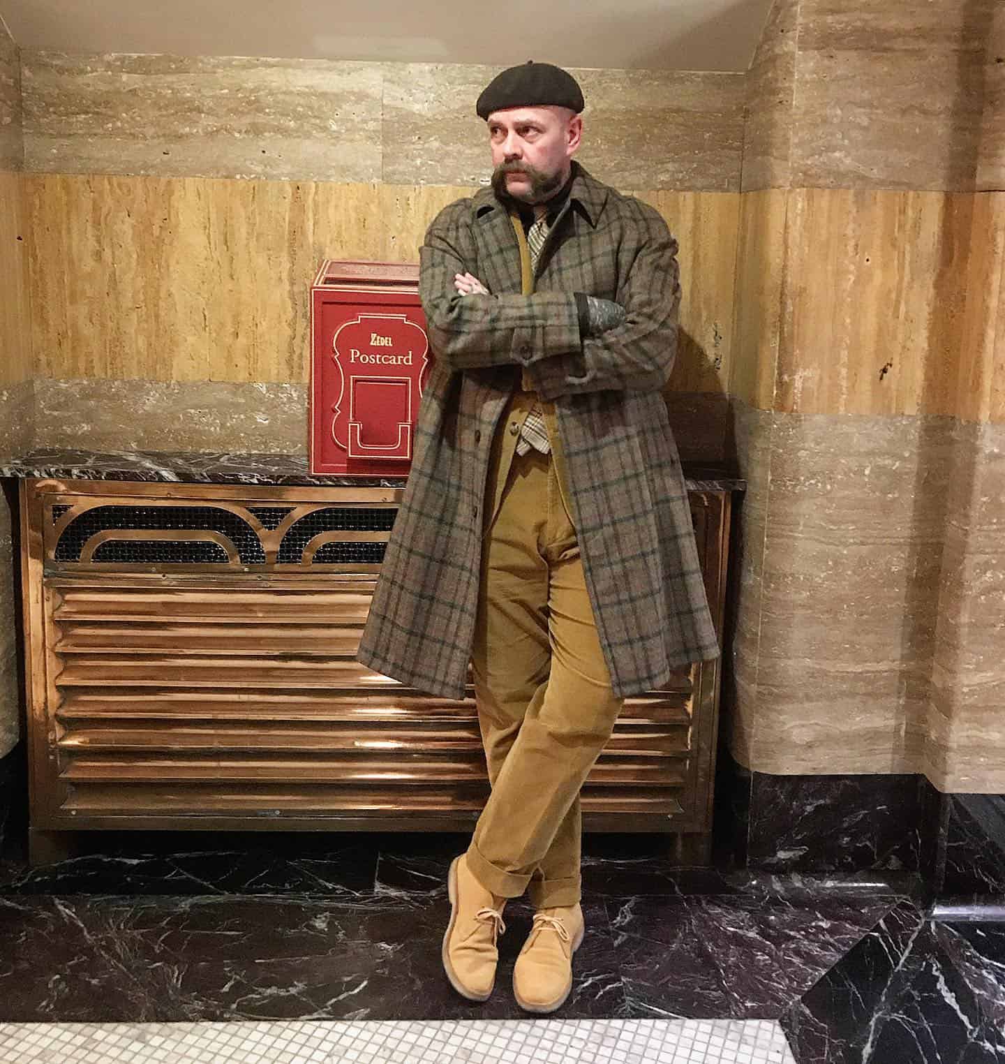 man wearing a bereta and checked long coat