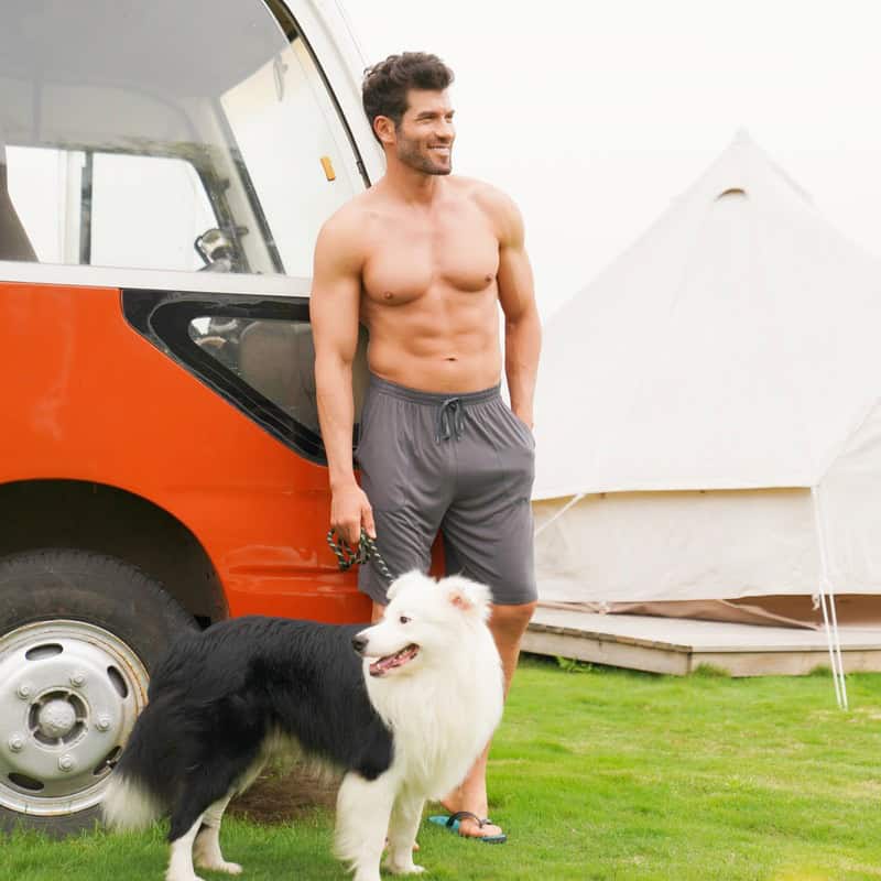 man in david archy pajama shorts and holding a dog's leash