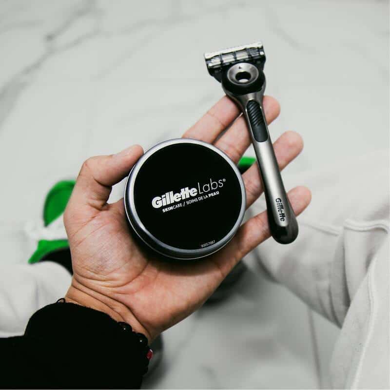 holding a shaving cream and a 5 blade razor by gillette labs