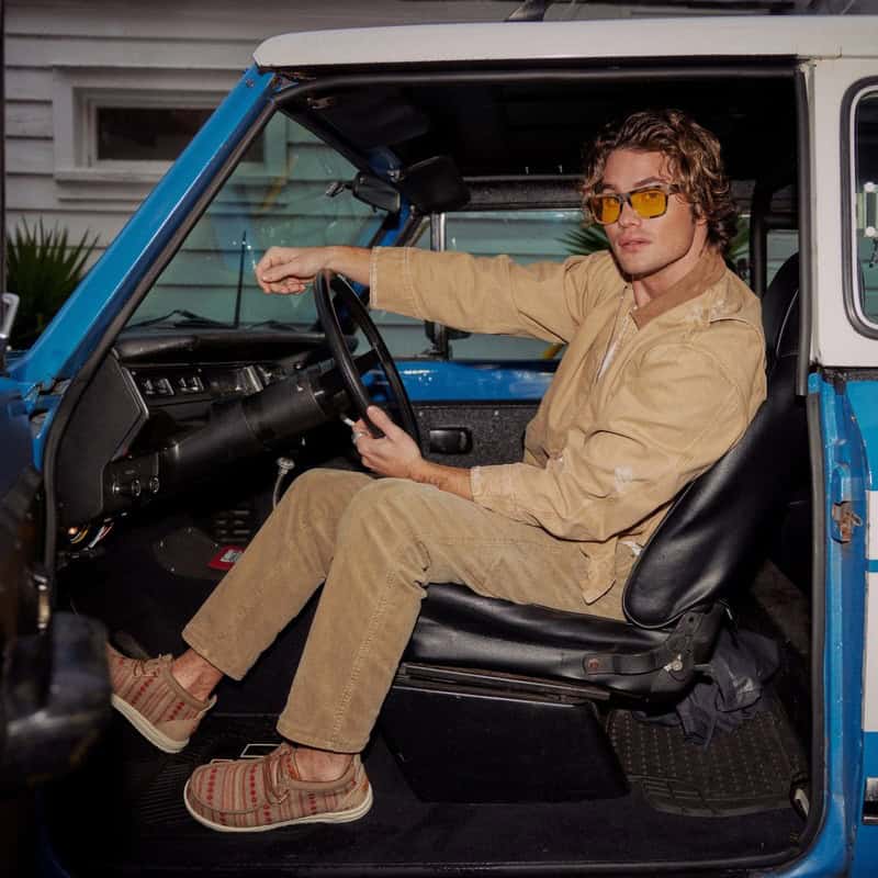man sitting on the driver seat wearing a pair of heydude wally shoes