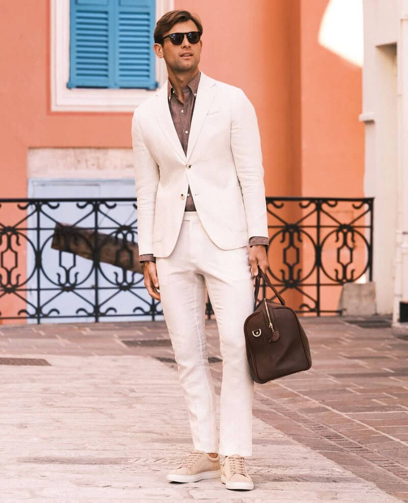 man carrying a weekender bag wearing a linen suit