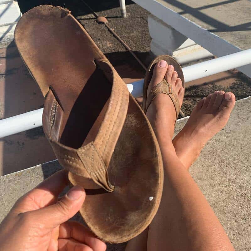 man holding a worn out rainbow sandal