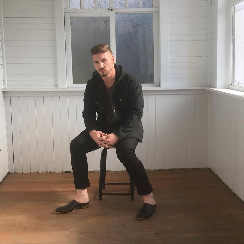 man sitting on a stool wearing an all black outfit