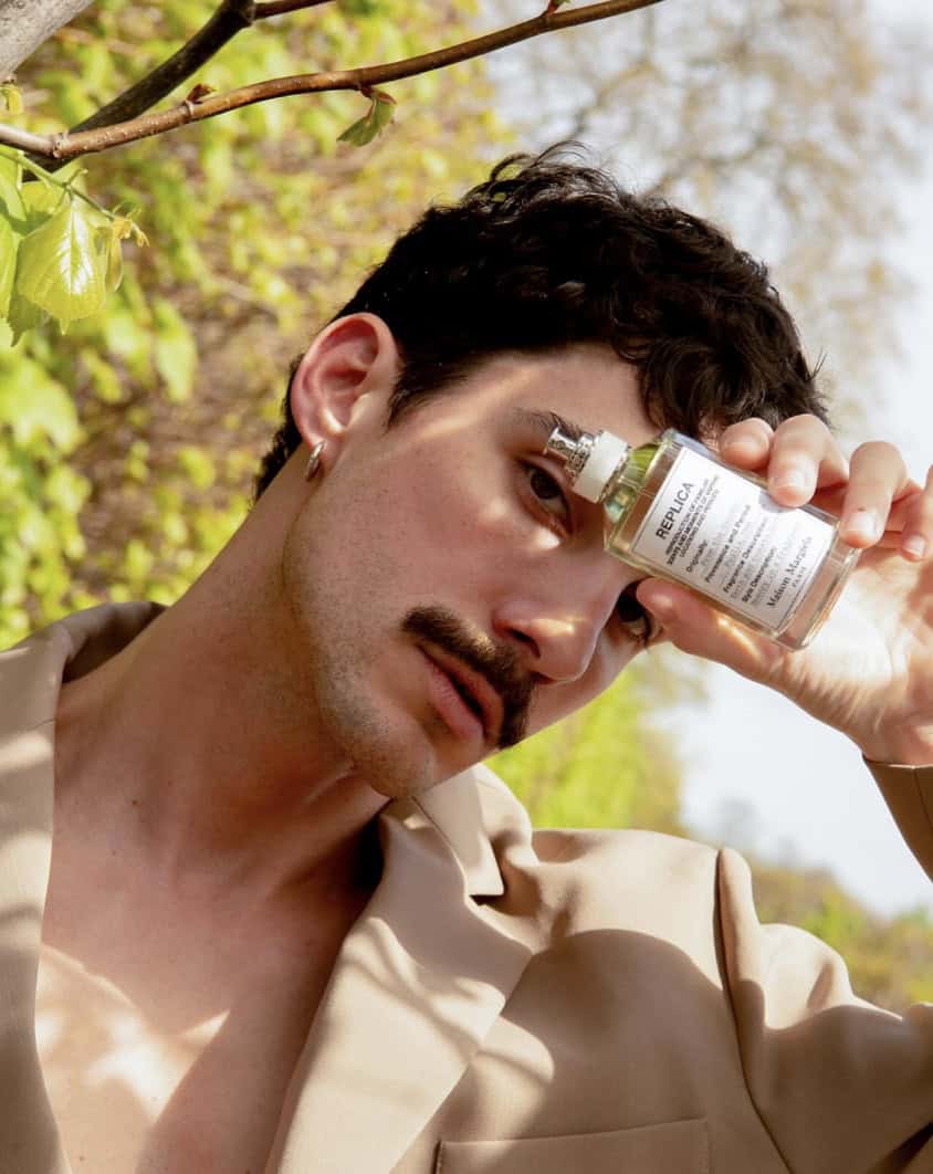 Model holding up a bottol of maison margiela fragrances to help show the best ways to wear cologne
