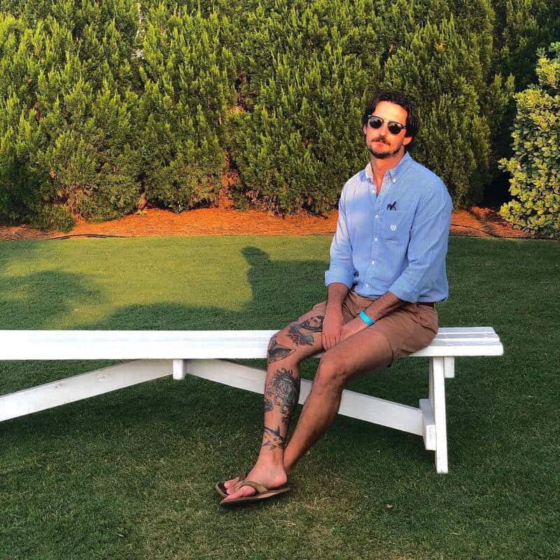man sitting on a bench wearing a blue shirt and brown shorts