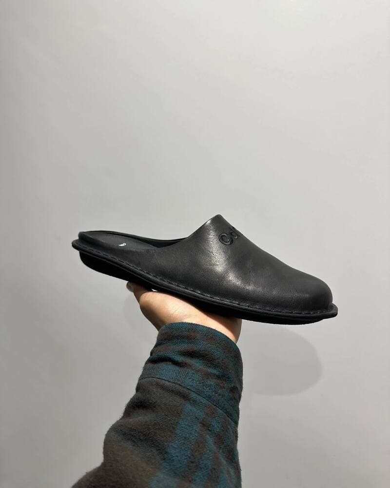 a black leather mules on the palm of the hand